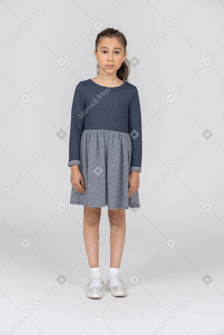 Vista frontal de una chica con ropa informal de pie con los brazos a los lados