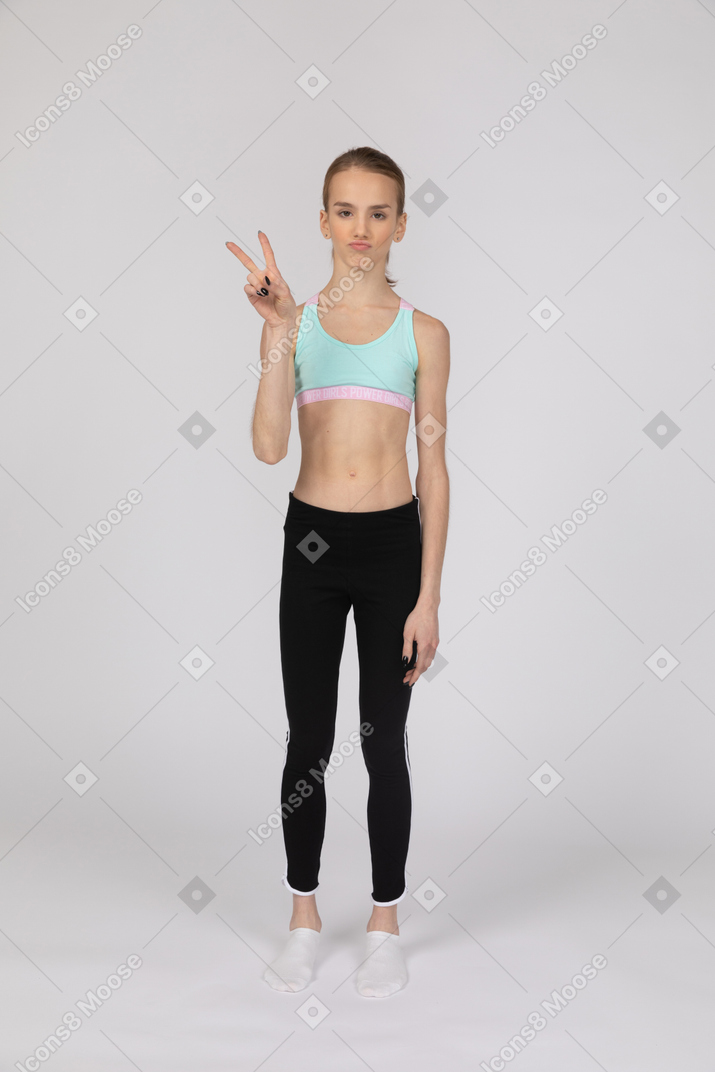 Teen girl in sportswear making peace sign