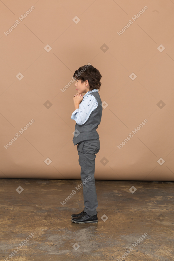 Вид сбоку задумчивого мальчика в сером костюме