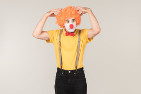 Troubled looking male clown touching wig he's wearing