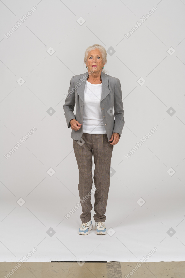 Front view of an old lady in suit jumping