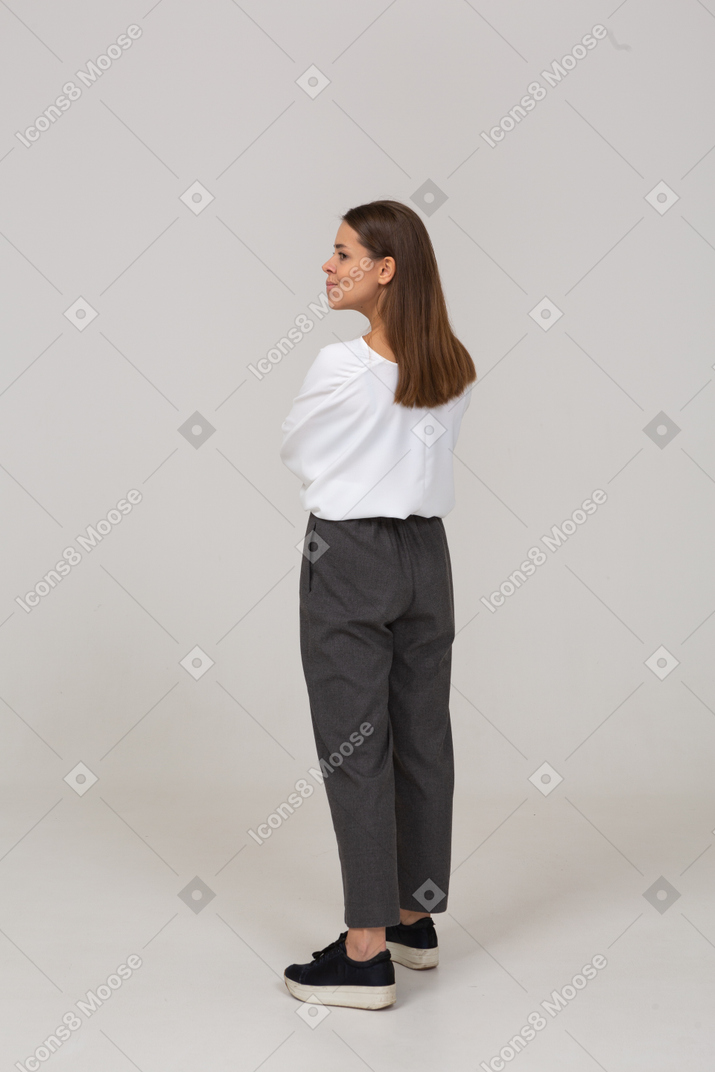 Three-quarter back view of a young lady in office clothing looking aside