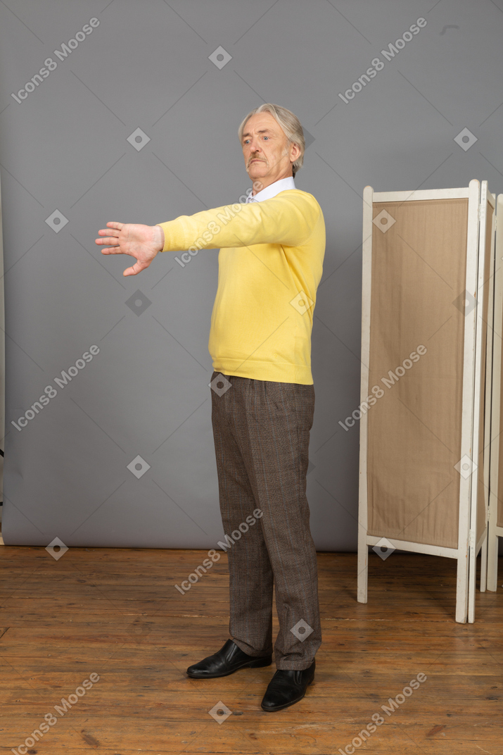 Vista de tres cuartos de un anciano disgustado extendiendo su mano