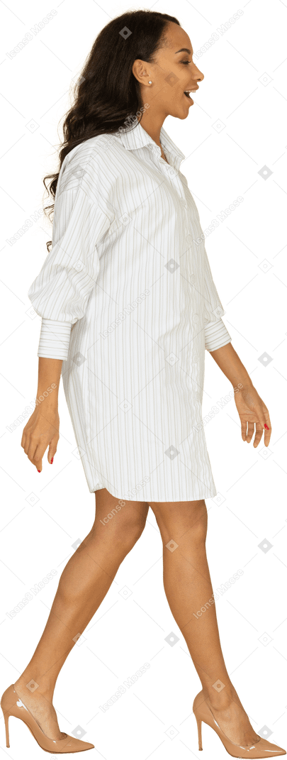 Vue latérale d'une jeune femme souriante à la peau foncée en robe blanche