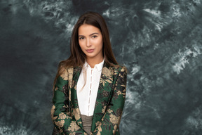 Close-up a young businesswoman in silk jacket looking at camera