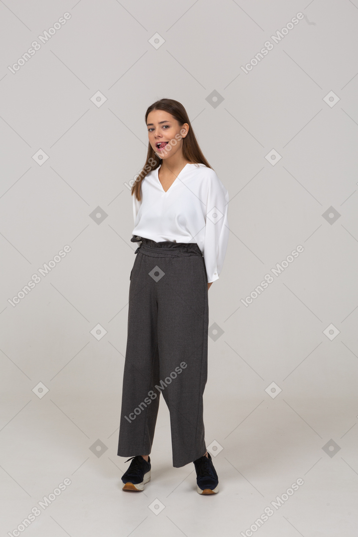 Front view of a sly young lady in office clothing holding hands behind