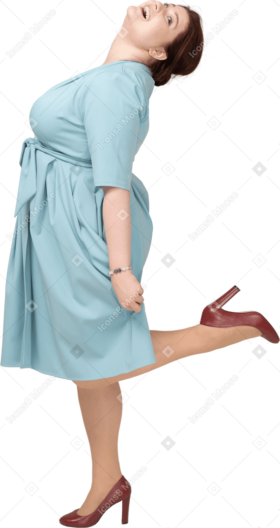 一个穿着蓝色连衣裙的女人在一条腿上保持平衡的侧视图