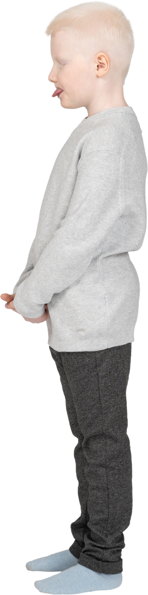 Vista lateral de un niño chico en ropa casual mostrando lengua