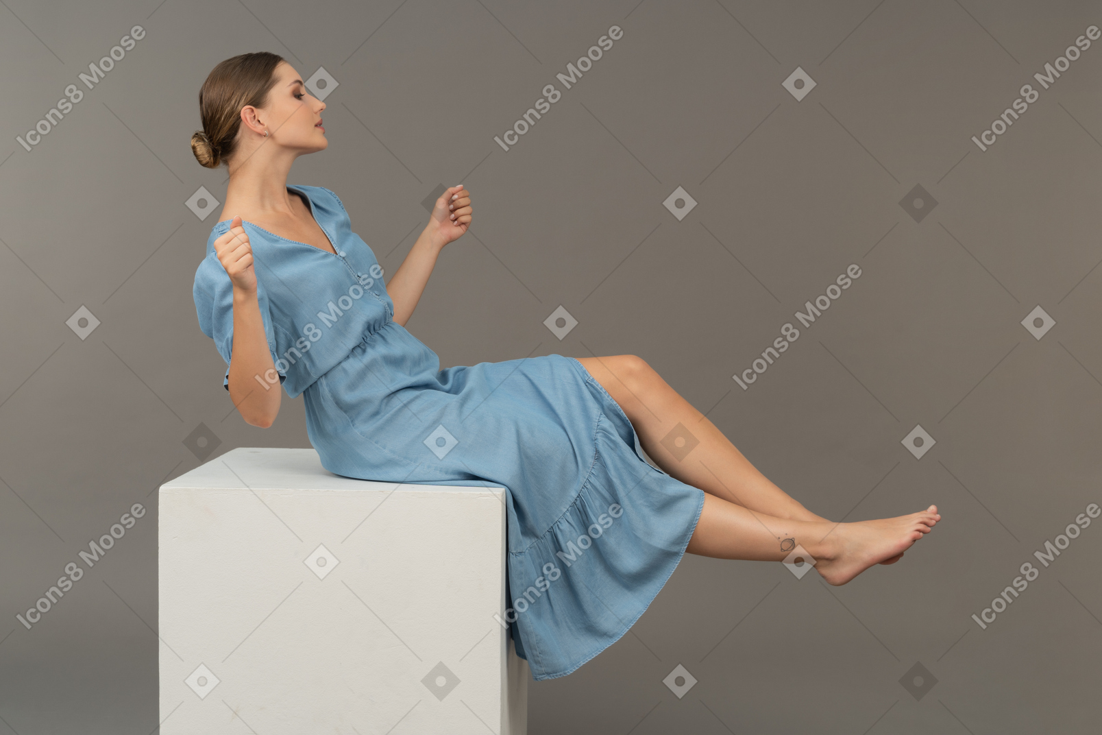 Vista lateral da jovem sentada no cubo e tentando manter o equilíbrio