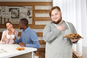 A barista holding a plate of cookies in a coffee shop