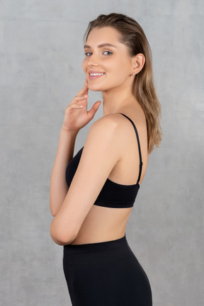 Vista lateral de uma jovem em roupas esportivas pretas sorrindo