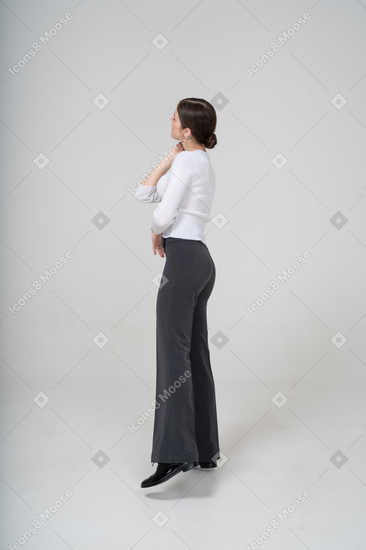 Vista lateral de uma mulher de calça preta e blusa branca apoiada em uma perna só