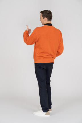 Junger mann im orangefarbenen sweatshirt stehend