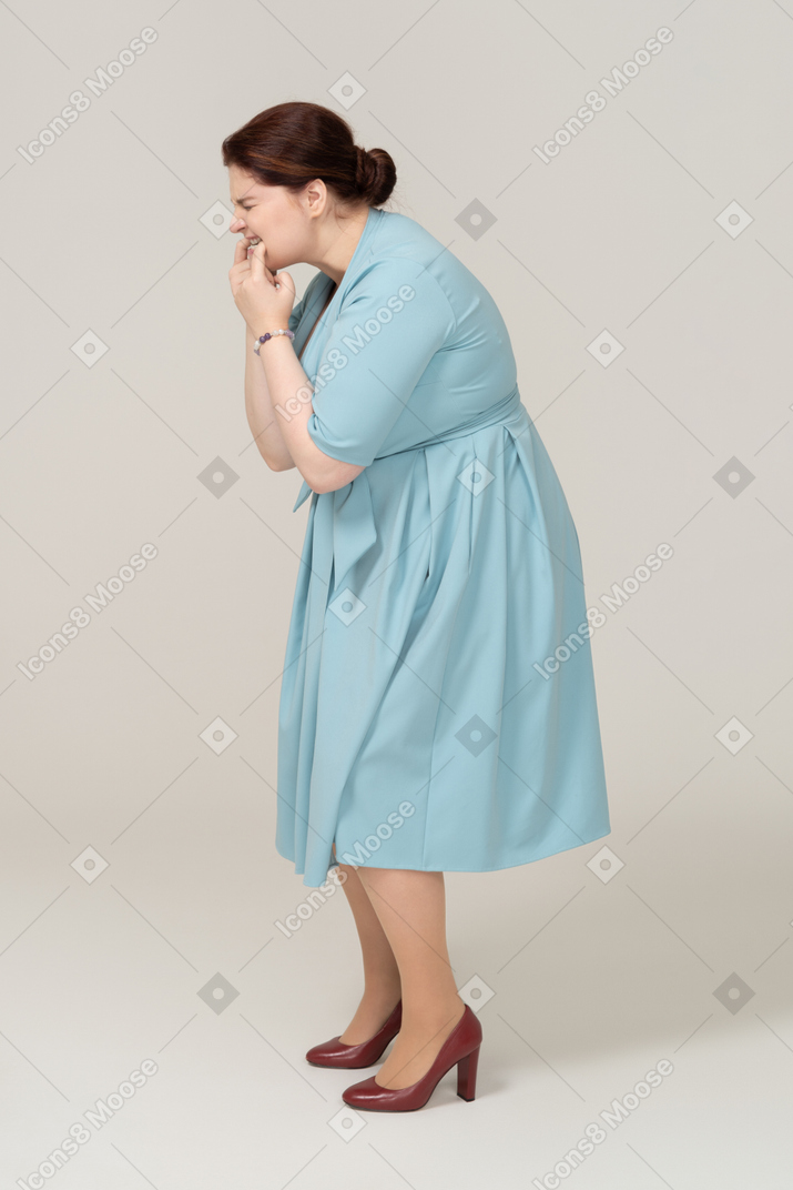 Side view of a woman in blue dress whistling