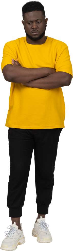 Vista frontal de um jovem de pele escura em uma camiseta amarela cruzando os braços