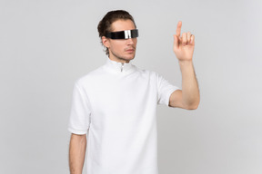 Un joven con gafas futuristas trabajando con una interfaz virtual.