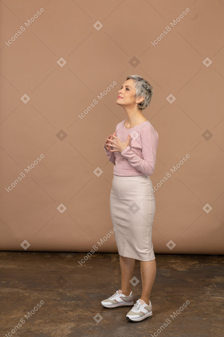Vue latérale d'une femme en vêtements décontractés posant avec les mains sur la poitrine