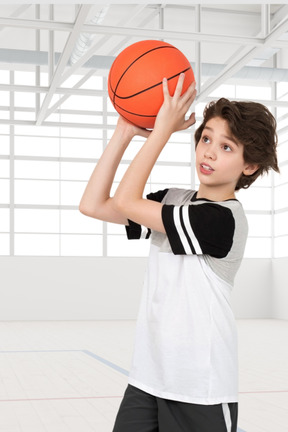 A young boy holding a basketball in a gym
