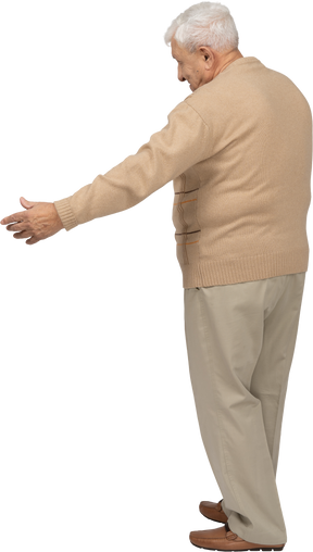 Вид сбоку на старика в повседневной одежде, стоящего с протянутыми руками
