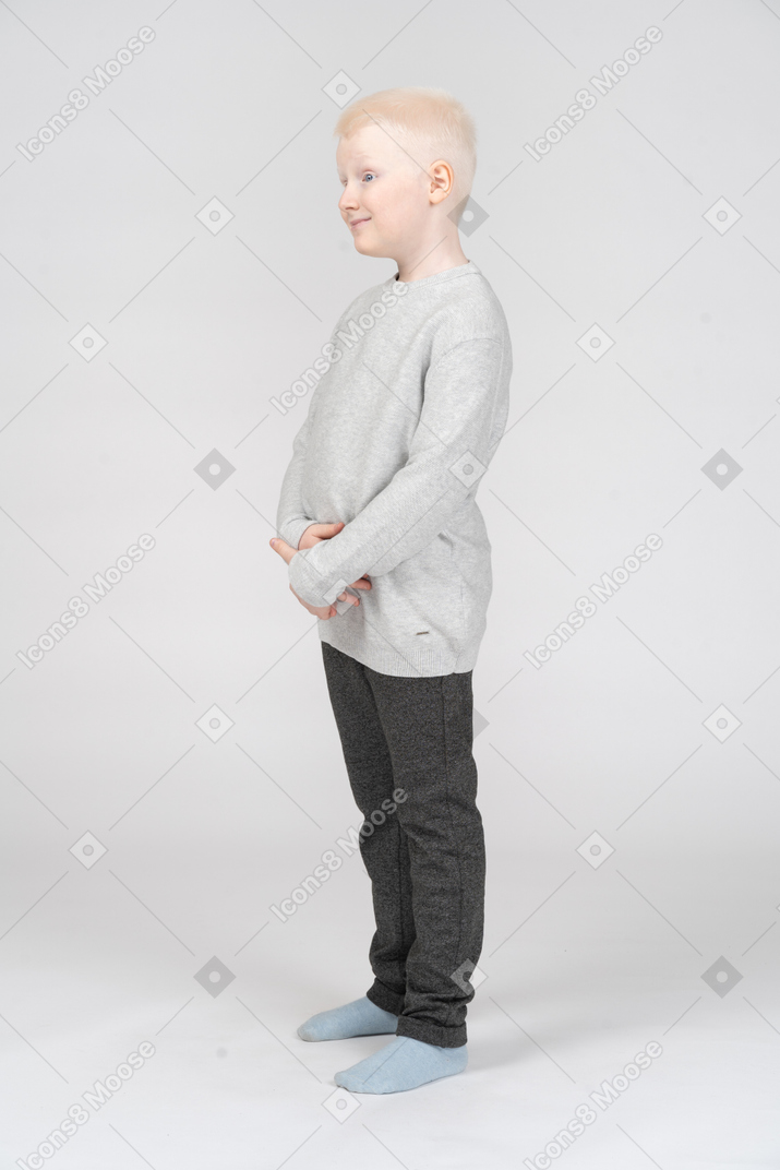 A figura intera di un bambino maschio biondo carino che tocca la sua pancia