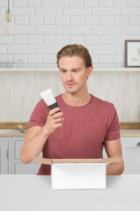A man holding a cream tube in a kitchen