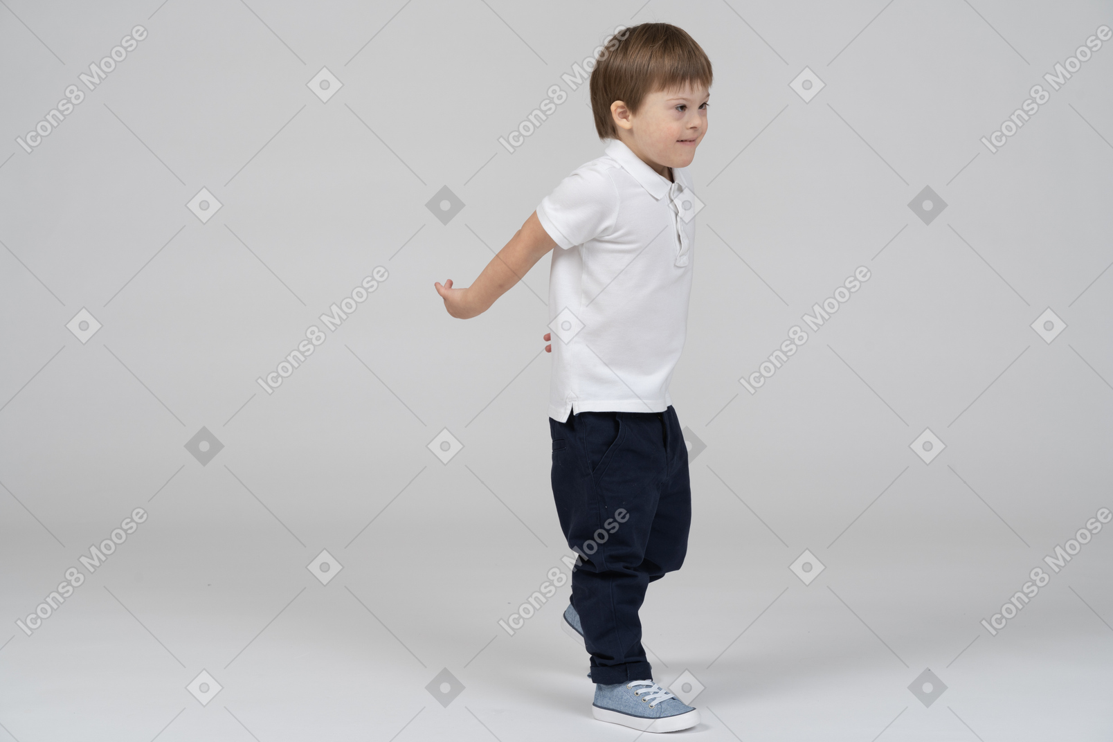Three-quarter view of a boy stepping forward with hands behind his back