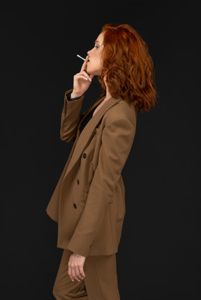 一个穿着棕色西装的女人抽烟的侧视图