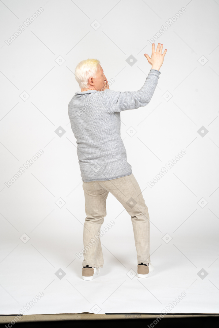 Hombre de pie con el brazo levantado hacia la cámara y gritando