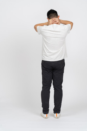Rear view of a man in casual clothes standing with hands on neck