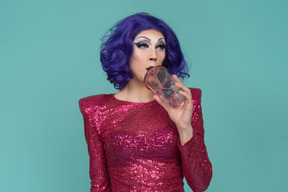 Drag queen in pink sequin dress having a drink from plastic cup