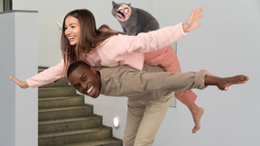 Young interracial couple piggybacking with cat with rage face