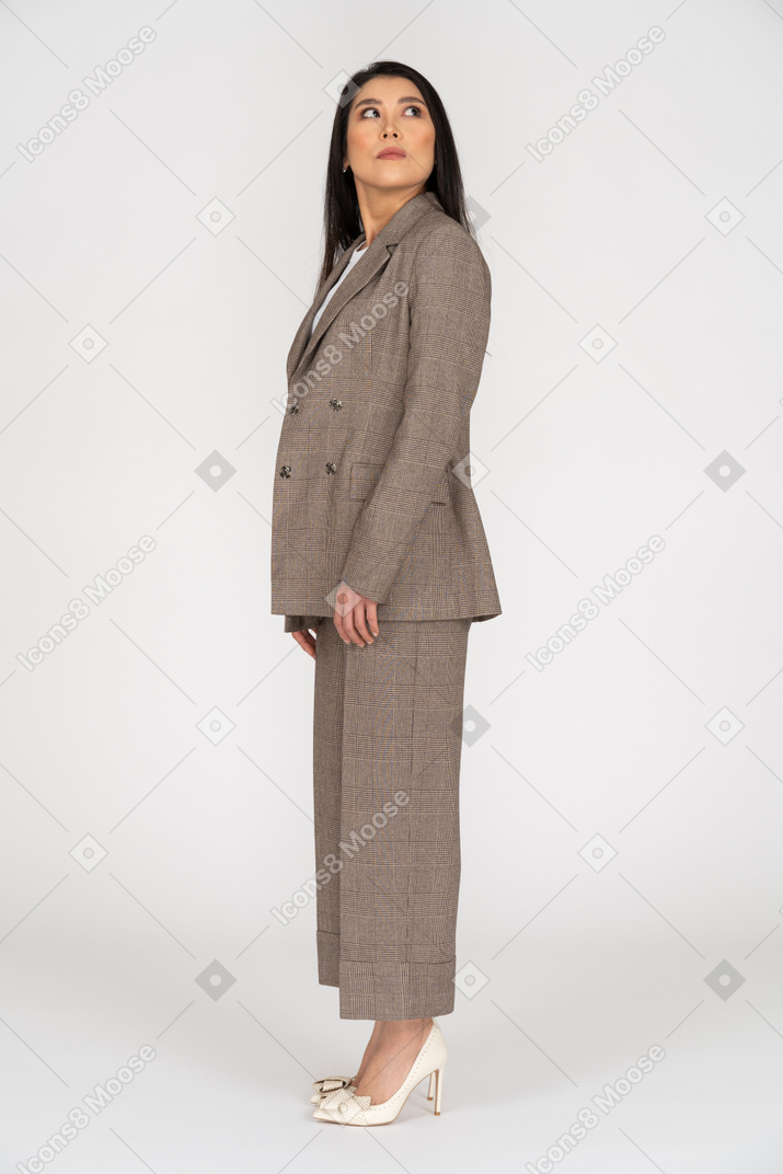Side view of a young lady in brown business suit turning head and looking aside