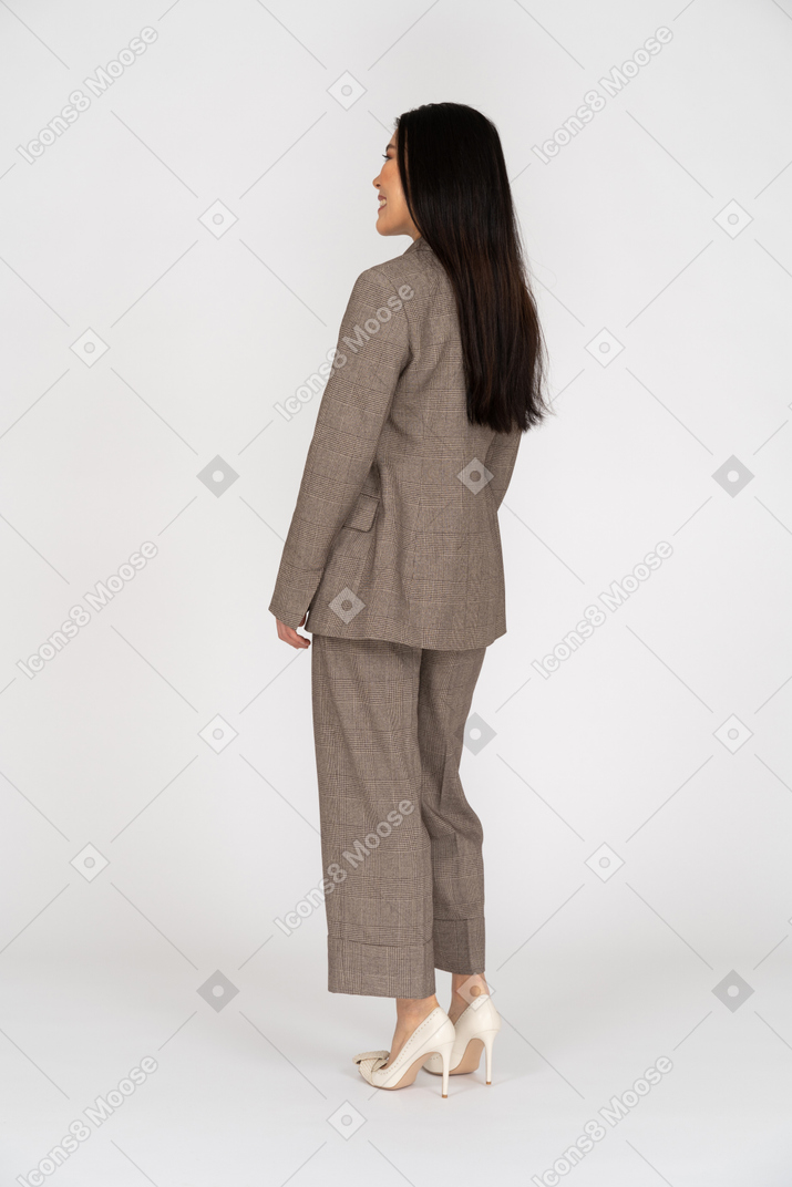 茶色のビジネススーツで笑顔の若い女性の4分の3の背面図