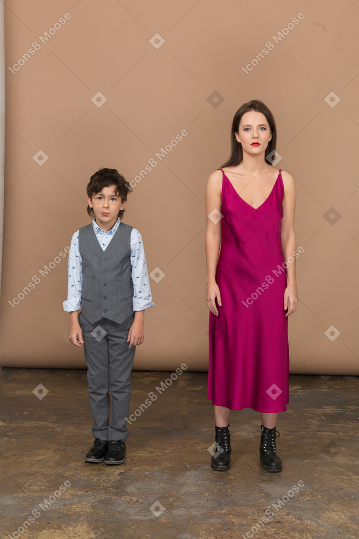 Вид спереди мальчика в жилете костюма и молодой женщины