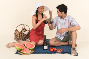 Young interracial couple having picnic and saying cheers