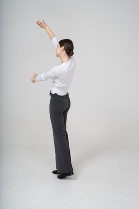 Vue latérale d'une femme en pantalon noir et chemisier blanc montrant la taille de quelque chose
