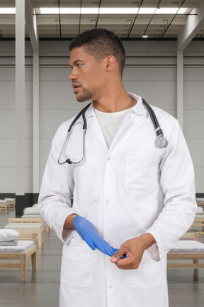 Man in a white lab coat taking off a medical glove