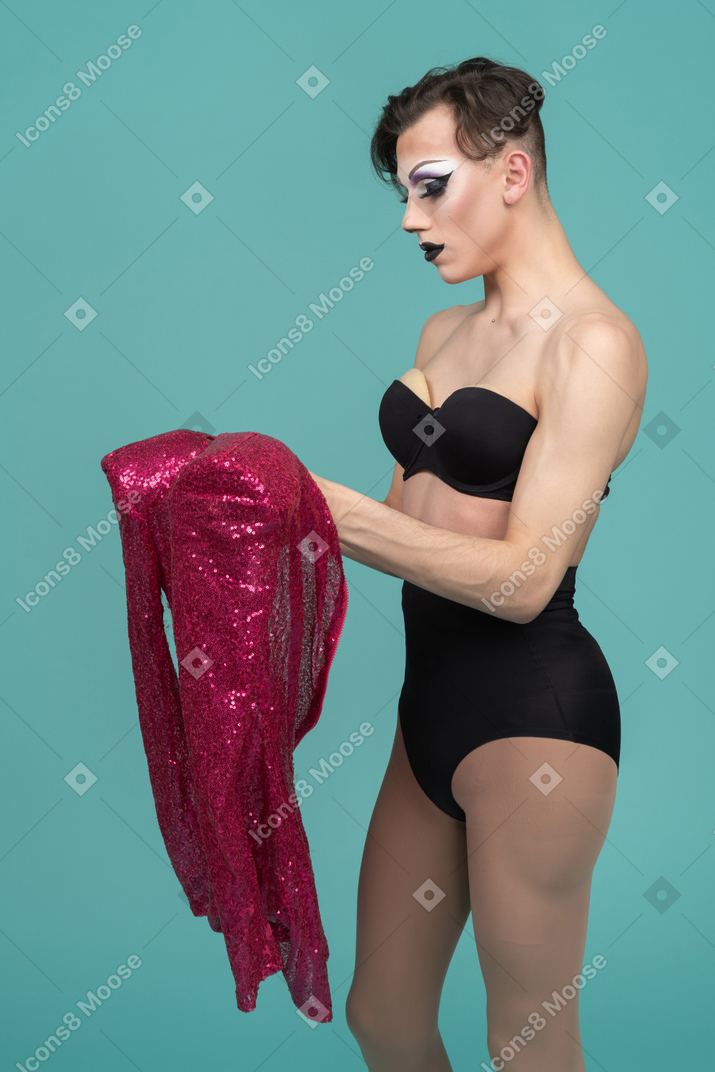 Side view of a drag queen holding pink sequin dress