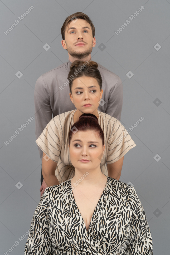 Deux jeunes femmes et un homme debout dans une rangée