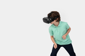 Boy in virtual reality headset standing in fighting position