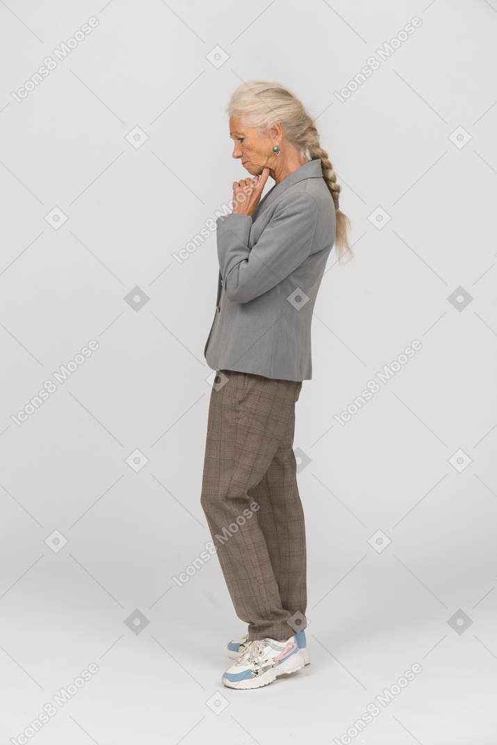 Thoughtful old lady in suit standing in profile