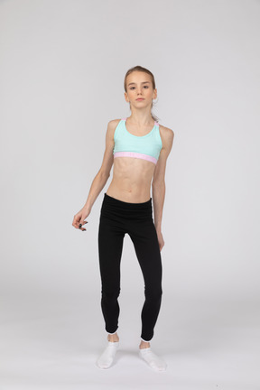 Vista frontal de una jovencita en ropa deportiva doblando las rodillas