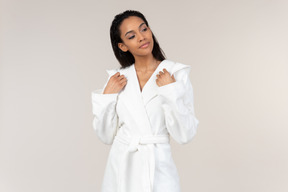 Black woman in white bathrobe going about her morning routine