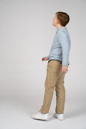 Side view of a boy standing on one leg and looking up