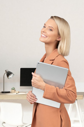 A woman standing in front of a desk holding a tablet