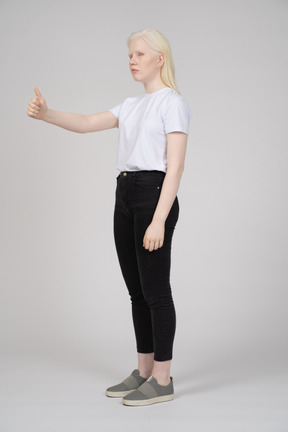 Вид в три четверти на молодую девушку с поднятыми большими пальцами
