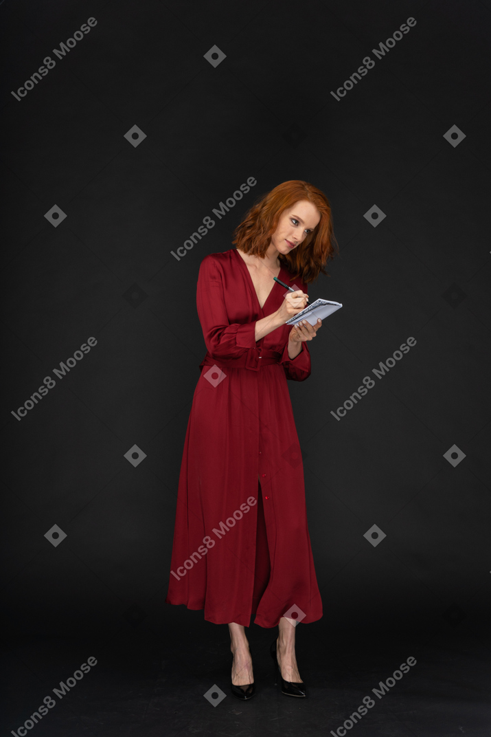 Woman standing and writing in a notebook