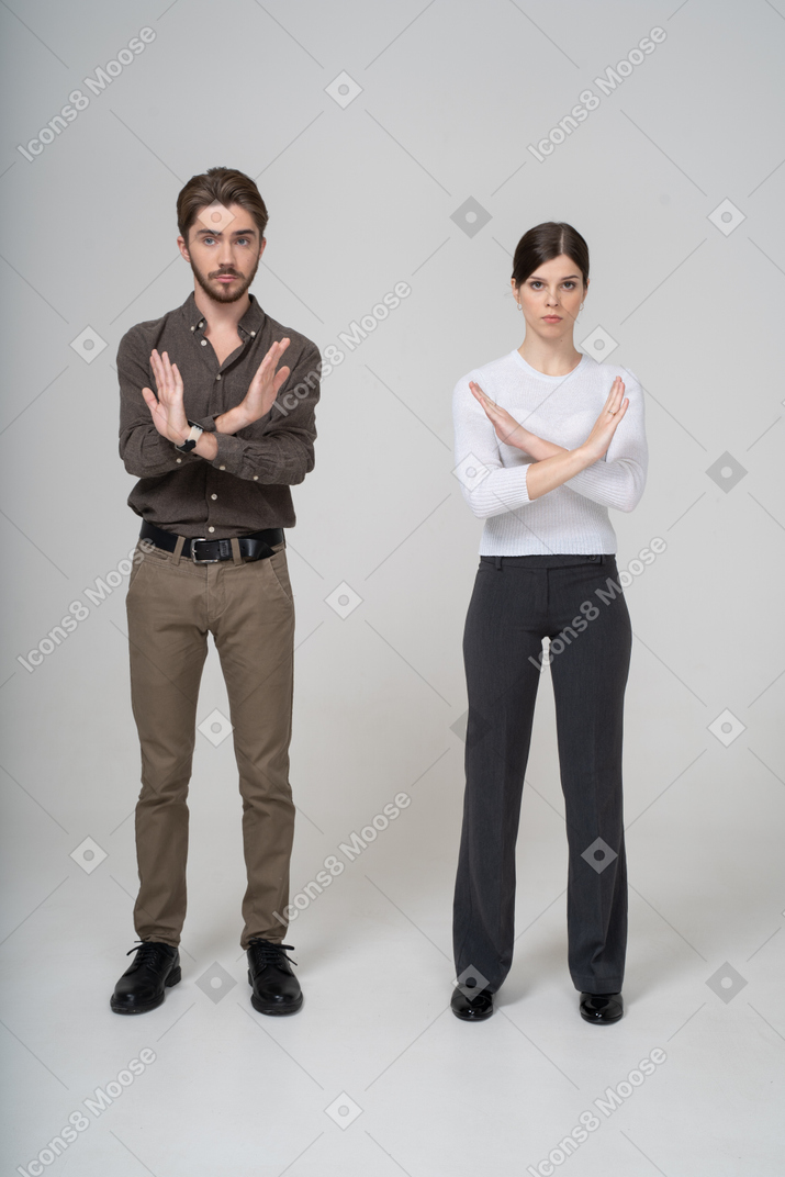 一对年轻夫妇在办公室服装交叉双臂的前视图