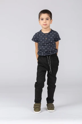 Front view of a boy in casual clothes standing with hands behing back