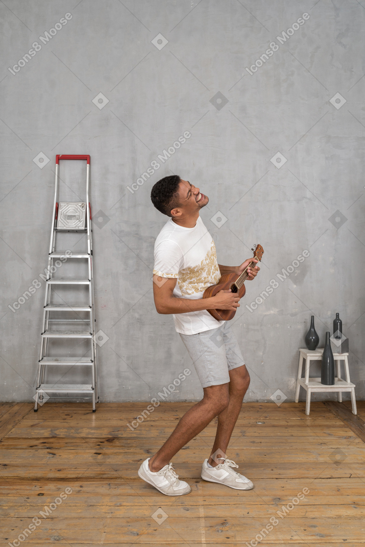 Vista lateral de um homem tocando ukulele e se divertindo